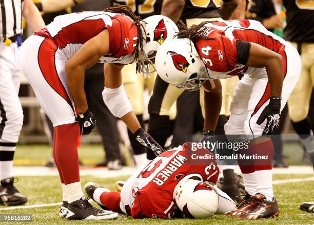 Quarterback Kurt Warner of the Arizona Cardinals lies on the field as he is tended to by teammates Larry Fitzgerald and Tim Hightower after he took a...