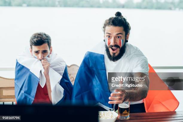 happy french national soccer team supporter watching game with friend - france national soccer team stock pictures, royalty-free photos & images