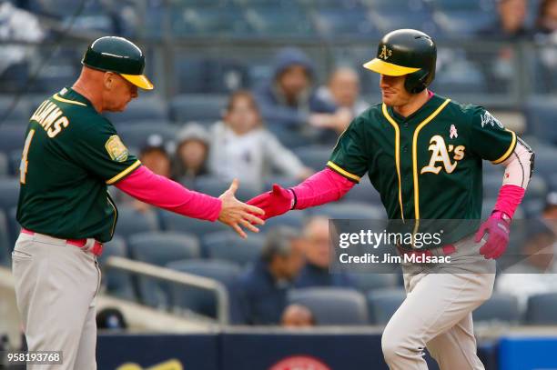 Mark Canha of the Oakland Athletics celebrates his ninth inning home run against the New York Yankees with third base coach Matt Williams at Yankee...