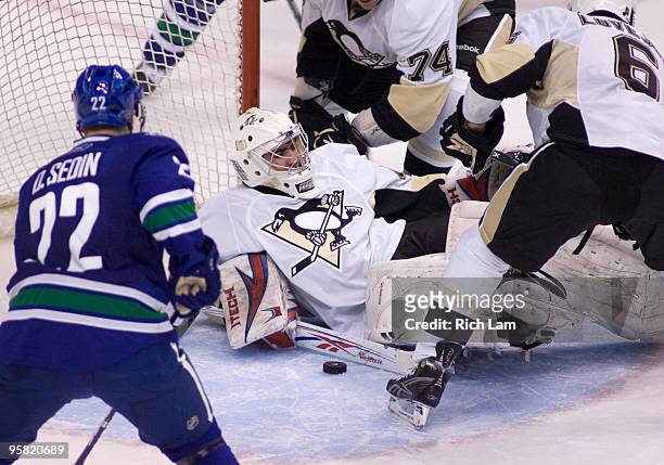 Goalie Alexander Pechurski of the Pittsburgh Penguins tries cover the loose puck while teammates Ben Lovejoy and Jay McKee and Daniel Sedin of the...