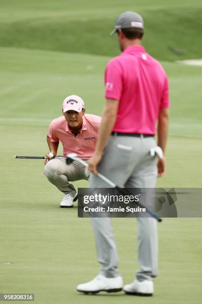 Danny Lee of New Zealand lines up a putt on the 12th green as Webb Simpson of the United States looks on during the final round of THE PLAYERS...