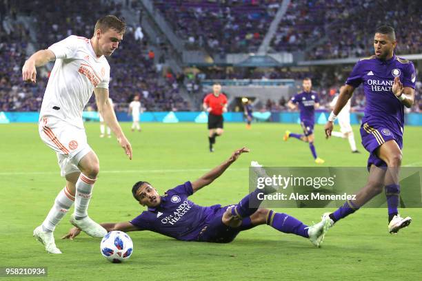 Julian Gressel of Atlanta United FC dribbles past a sliding Mohamed El-Munir of Orlando City SC during a MLS soccer match at Orlando City Stadium on...