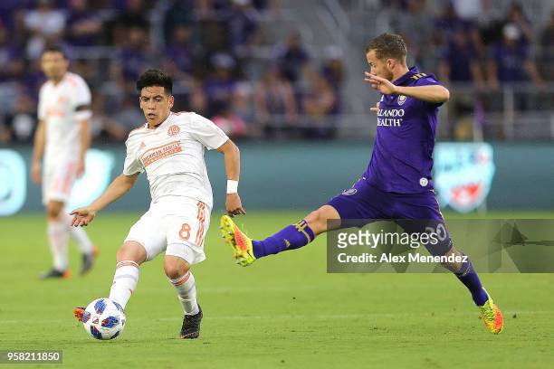 Ezequiel Barco of Atlanta United FC kicks the ball past a flying Oriol Rosell of Orlando City SC during a MLS soccer match at Orlando City Stadium on...