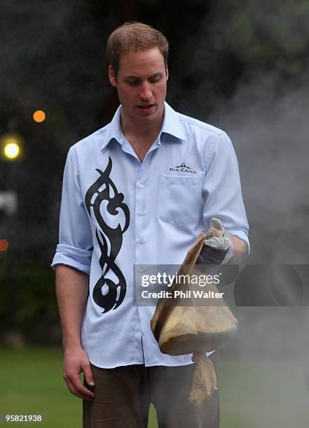 Prince William lifts a parcel of food out of the traditional Maori earth oven called a Hangi, at Government House on the first day of his visit to...