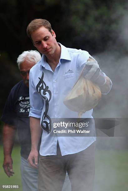 Prince William lifts a parcel of food out of the traditional Maori earth oven called a Hangi, at Government House on the first day of his visit to...