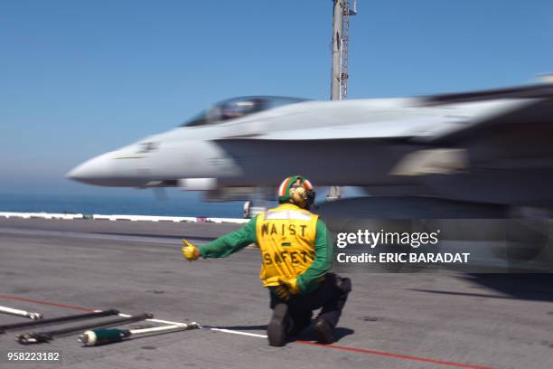 Catapult officer gestures as a US Navy F/18 Hornet takes off from the USS George H.W. Bush aircraft carrier on May 11, 2018 in the Atlantic Ocean. -...