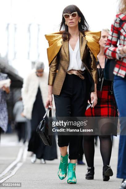 Guest wearing power shoulder golden jacket during Mercedes-Benz Fashion Week Resort 19 Collections at Carriageworks on May 14, 2018 in Sydney,...