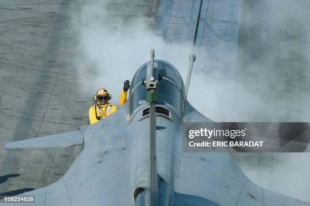 The steam from the aircraft catapult engulfs catapult officers as a French Rafale jet gets ready to take off from the deck of the USS George H.W....