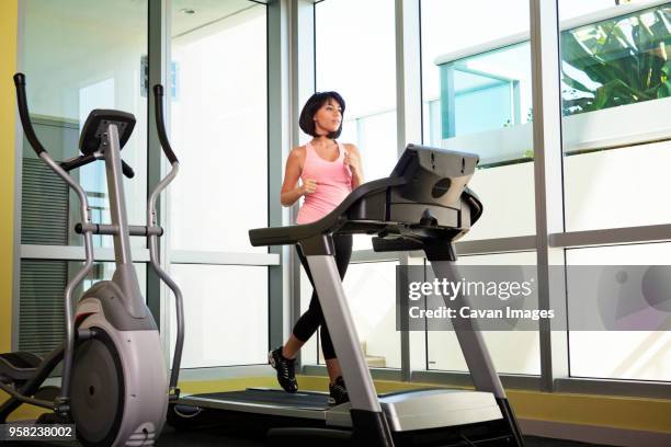 full length of woman exercising on treadmill in gym - トレッドミル　女性 ストックフォトと画像