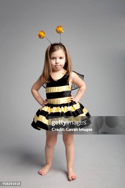 portrait of girl wearing bee costume while standing against gray background - tierkostüm stock-fotos und bilder