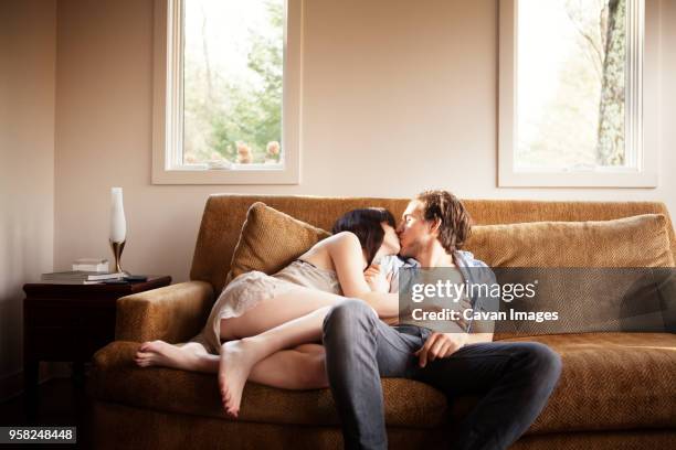 couple kissing while relaxing on sofa - peck stock pictures, royalty-free photos & images