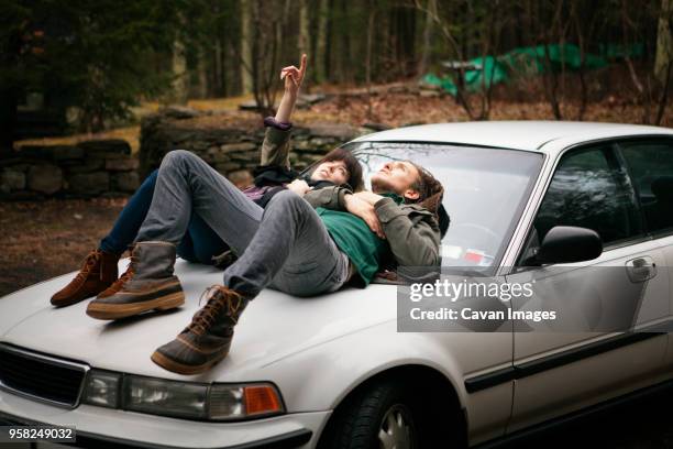 couple lying on car in forest - auto daten stock pictures, royalty-free photos & images