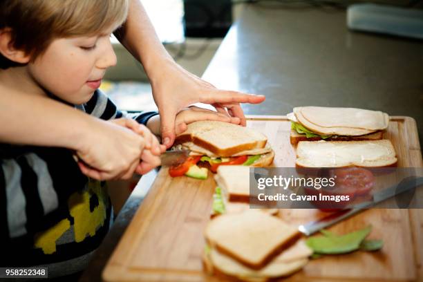 cropped image of father making sandwich with son in kitchen - making sandwich stock pictures, royalty-free photos & images