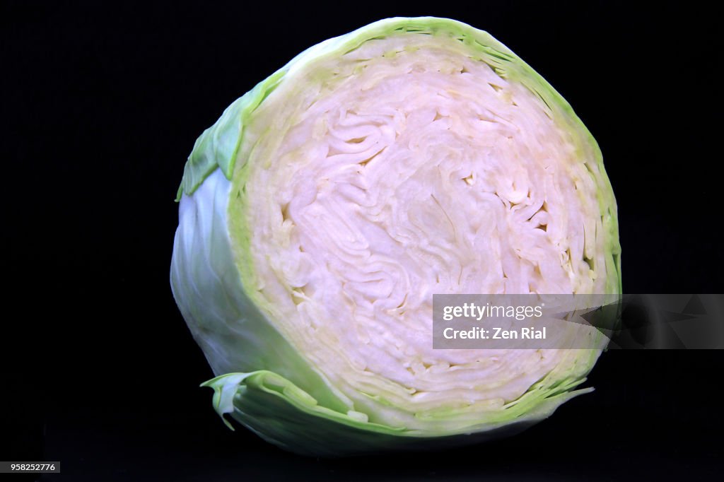 Cross section of a head of green cabbage (Brassica oleracea var. capitata) on black background