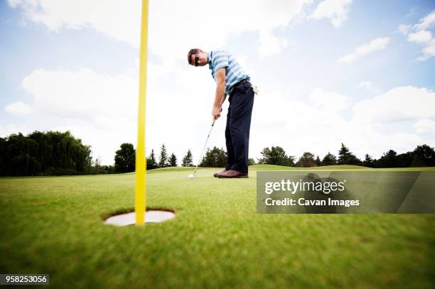 side view of golfer playing on field - bent golf club stock pictures, royalty-free photos & images