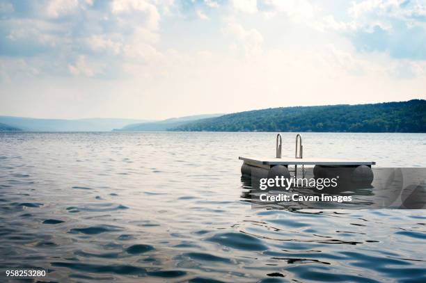 floating platform on lake against sky - floß stock-fotos und bilder