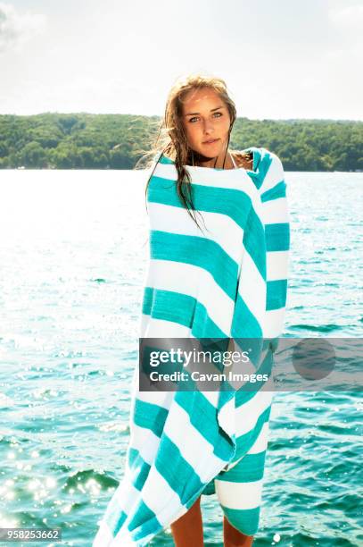 portrait of young woman wrapped in towel against lake - wrapped in a towel stock-fotos und bilder