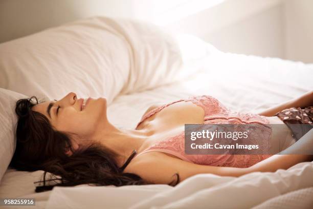 smiling woman with eyes closed lying on bed at home - alluring bildbanksfoton och bilder