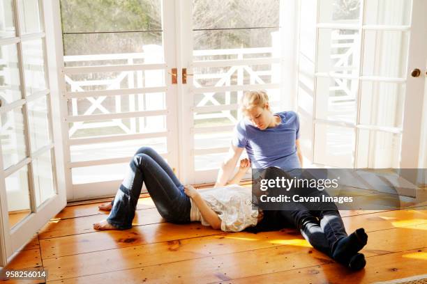 woman lying on mans lap at home - hartholz stock-fotos und bilder