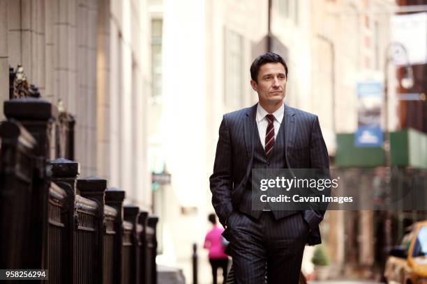 confident businessman walking on city street - wall street photos et images de collection