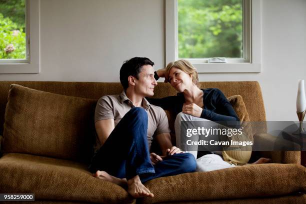 couple sitting on sofa at home - husband wife stock pictures, royalty-free photos & images