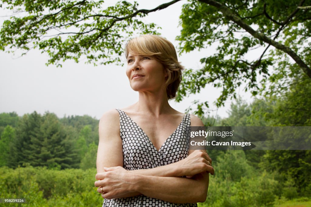 Woman with arms crossed standing against sky