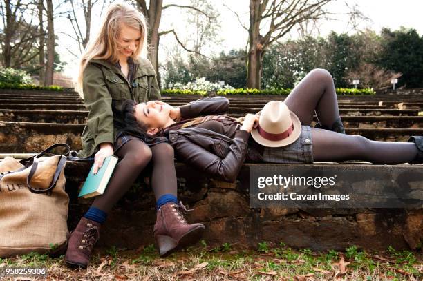 woman lying in friends lap at park - the raleigh stock-fotos und bilder