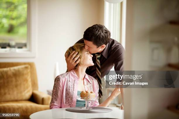 man kissing wife on forehead at home - kissing forehead stock pictures, royalty-free photos & images