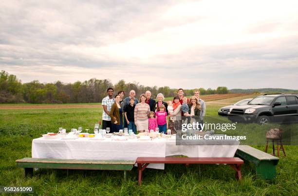 portrait of happy family standing on field during picnic - riunione di famiglia foto e immagini stock