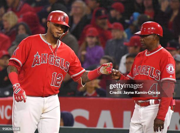 Martin Maldonado gets a fist pump from first base coach Alfredo Griffin of the Los Angeles Angels of Anaheim after a single in the game against the...