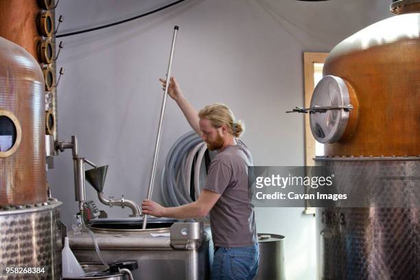 side view of worker stirring whiskey in machinery at distillery - spirit 32 ストックフォトと画像