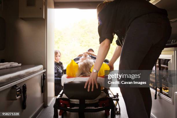 paramedics pushing hospital gurney in ambulance - stretcher stock-fotos und bilder