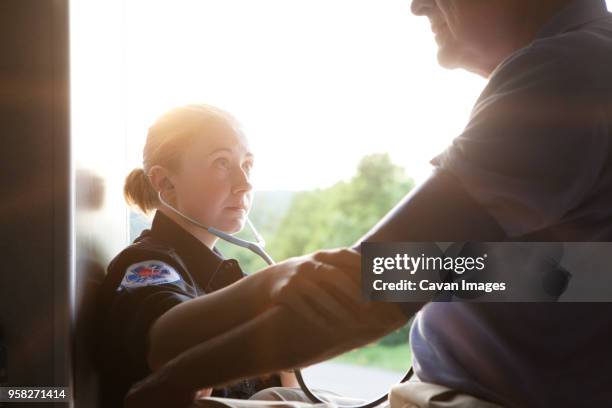 close-up of paramedic checking mans blood pressure in ambulance - personal de ambulancia fotografías e imágenes de stock