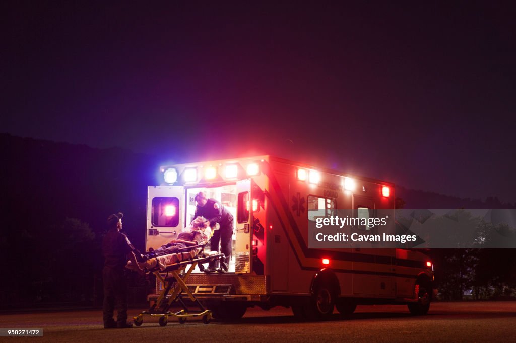 Paramedics carrying patient in ambulance at night