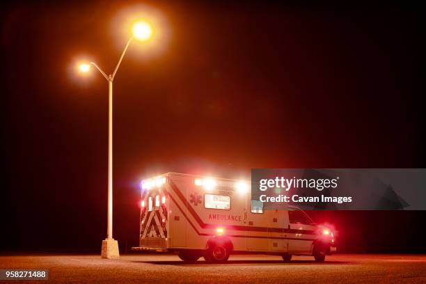 ambulance on road at night - blaulicht stock-fotos und bilder