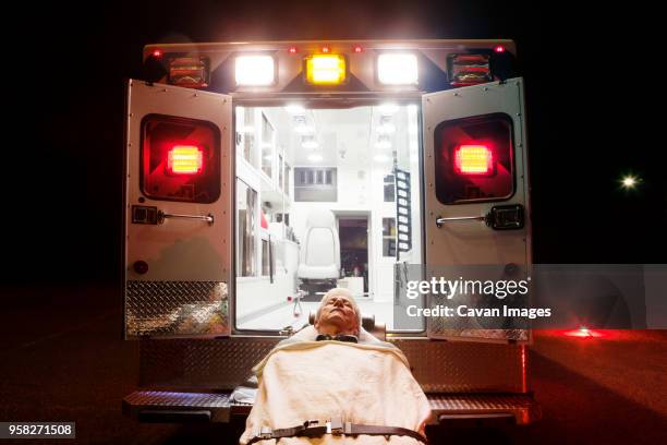 patient lying on hospital gurney by ambulance - stretcher stock-fotos und bilder