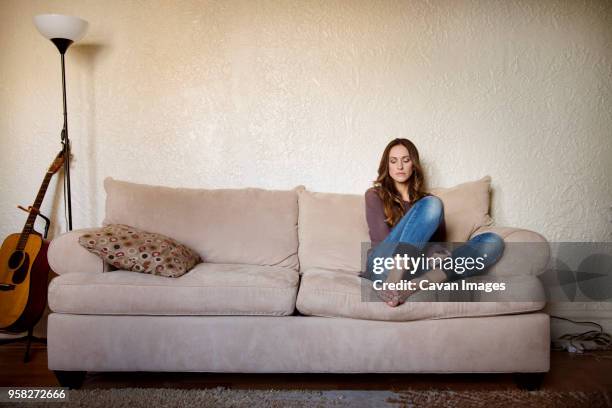 upset woman sitting on sofa at home - 'woman on couch stock pictures, royalty-free photos & images