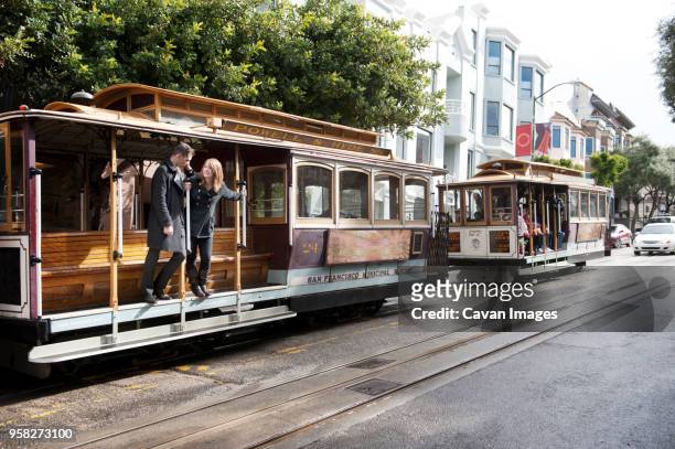 young couple standing on tramway at street - bay area stockfoto's en -beelden