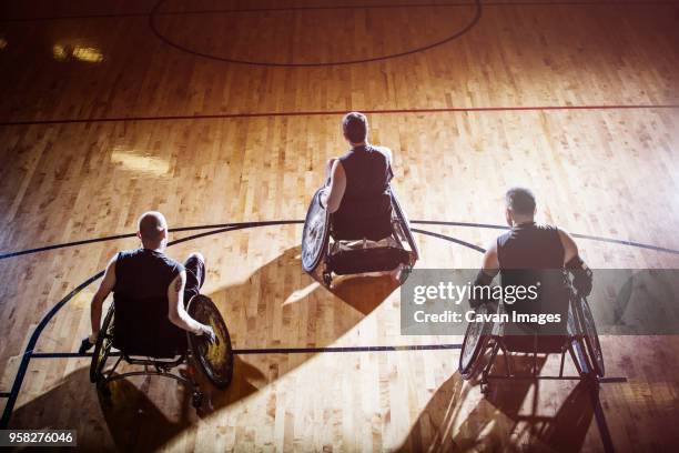 high angle view of men sitting on wheelchair in court - wheelchair rugby stock-fotos und bilder