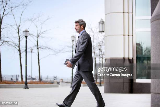 confident businessman walking on city street - business man profile fotografías e imágenes de stock