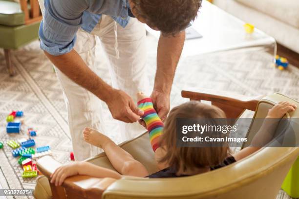 high angle view of father assisting girl in wearing sock at home - girls in socks stockfoto's en -beelden