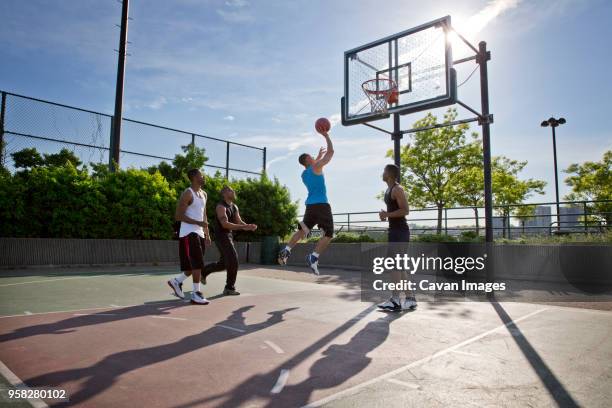 friends playing basketball in court on sunny day - usa court stock-fotos und bilder