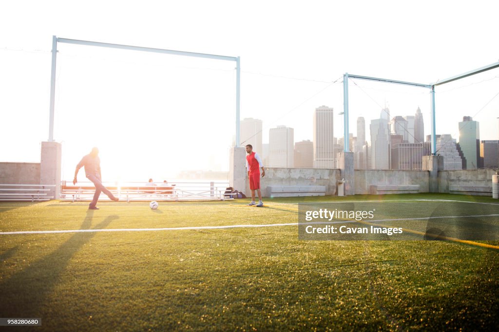 Father playing soccer with man on field during sunny day