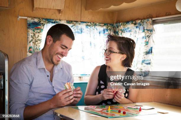 happy couple playing board game while sitting in camper van - the short game stock pictures, royalty-free photos & images