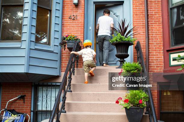 low angle view of father and son on steps outside house - family tree stockfoto's en -beelden