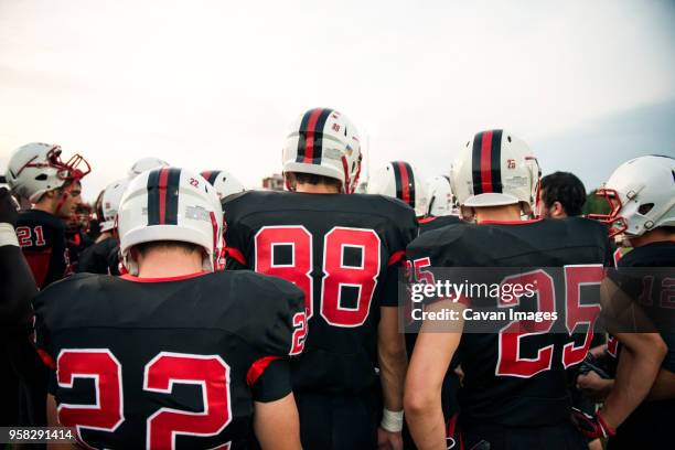 rear view of american football players against sky - high school sports equipment stock pictures, royalty-free photos & images