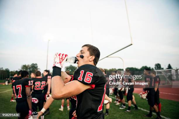 boy drinking water on american football field against sky - safety american football player stockfoto's en -beelden