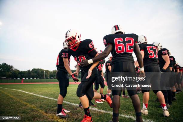 american football team practicing on grassy field against sky - safety american football player stockfoto's en -beelden