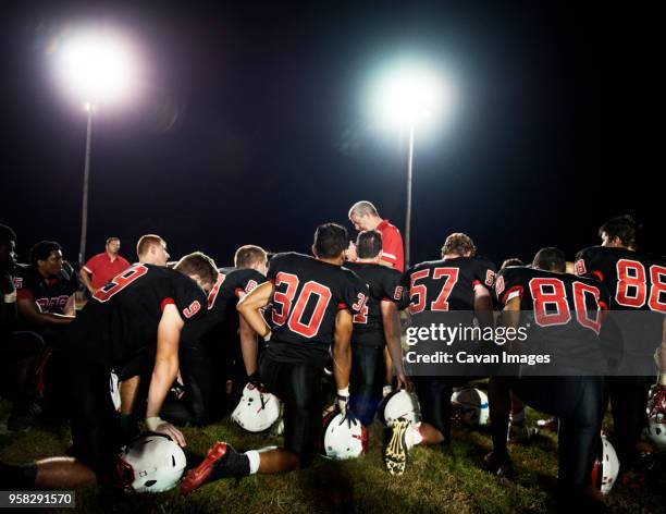 rear view of american football players kneeling on illuminated field at night - safety american football player 個照片及圖片檔