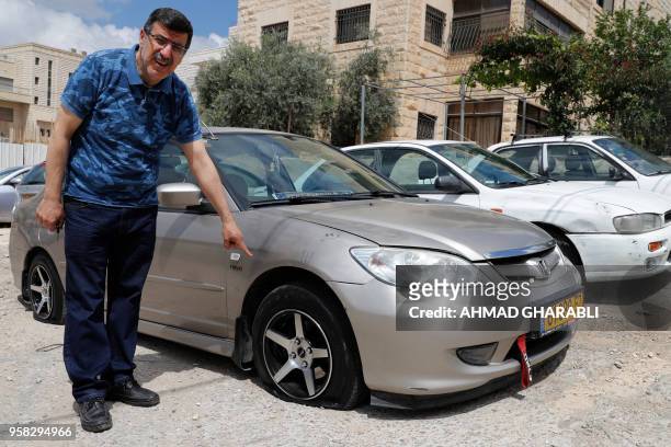 Palestinian man shows a car whose tyres were slashed in the latest "price tag" attack in the Palestinian neighborhood of Shuafat in Israeli annexed...